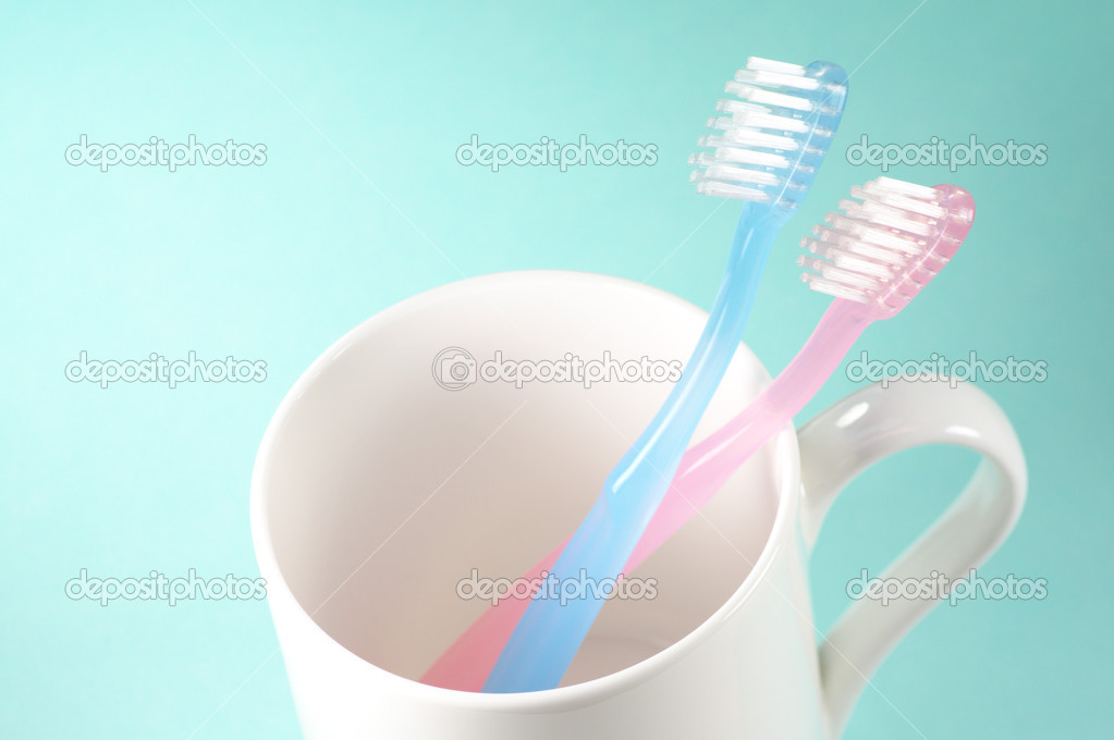 Two toothbrushes and a cup.
