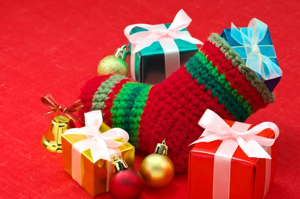 Meia de Natal e presentes de Natal coloridos em tecido vermelho — Fotografia de Stock