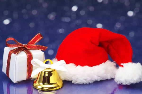Petit cadeau de Noël et chapeau de Père Noël sur fond blanc scintillant — Photo
