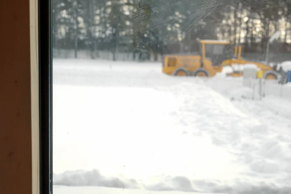 a tractor removing the snow, view from a window