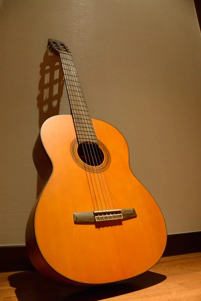 Una guitarra clásica apoyada contra una pared — Foto de Stock