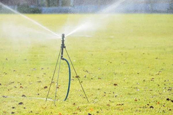 Tripod type Sprinkler in lawn field — Stock Photo, Image
