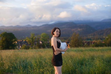 Bir tarlada duran, şapkasını tutan ve güneşe bakan bir kadın, yazı için yer, atmosferik destansı an