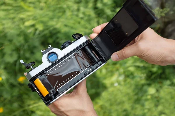 Eller SLR kamerasına film yüklüyor.