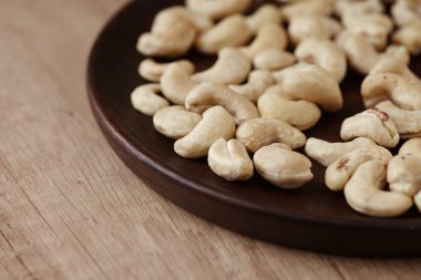 Ahşap bir masada, ahşap bir tabakta lezzetli fındıklar, yan görüş. Kapat.