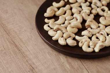 Ahşap bir masada, ahşap bir tabakta lezzetli fındıklar, yan görüş. Kapat.