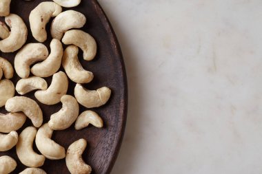 Ahşap bir tabakta, mermer masanın üstünde, nefis fındıklar, üst manzara. Metin için boşluk
