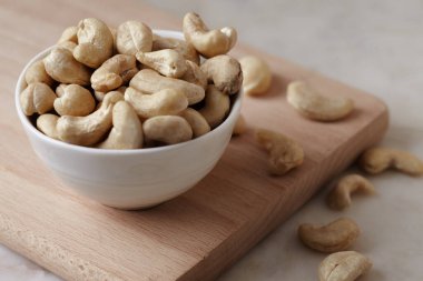 Tahta bir tahta kesme tahtasının üzerinde kasede fındık, mermer masa, kenar görüş. Metin için boşluk