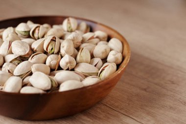 Tahta bir masada, yan manzaralı bir kasede fıstıklı fındık. Metin için boşluk