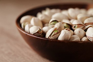 Tahta bir masada, yan manzaralı bir kasede fıstıklı fındık. Metin için boşluk