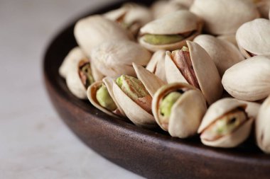 Ahşap bir masada ahşap bir tabakta fıstıklı fındıklar, yan görüş. Kapat.