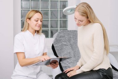 Kozmetoloji kliniğinde danışmanlık. Profesyonel kadın güzellik doktoru güzel bir bayanla konuşuyor..