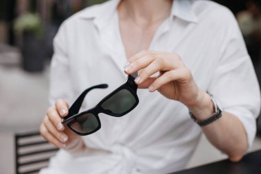 Sokakta kadın eli güneş gözlüğü tutuyor.