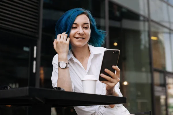 Genç ve çekici bir kadın boş zamanlarında kahve dükkanının önünde tek başına otururken selfie çekiyor.