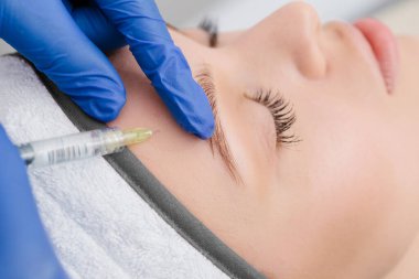 Kafasında havluyla iğne olan kadınların yakın plan portresi..