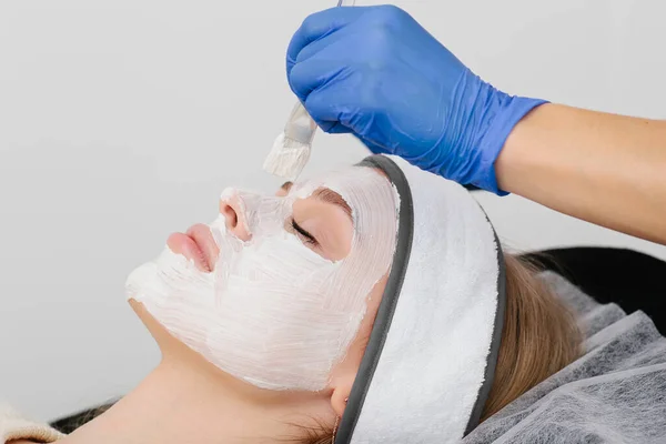 Kafasında havlu olan ve maske takan kadınların yakın plan portresi.