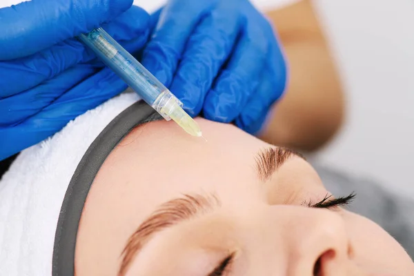 Kafasında havluyla iğne olan kadınların yakın plan portresi..