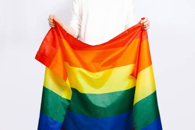 Gurur bayrağı, LGBTQ bayrağı, beyaz arka planda kadın ellerinde gökkuşağı bayrağı