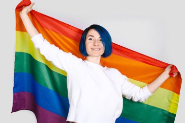 Igbtq konsepti. Stüdyoda mavi saçlı, gökkuşağı bayrağı taşıyan pozitif kadınlar izole edilmiş.