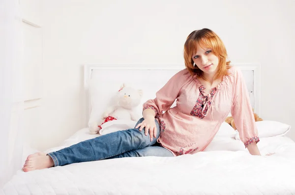 The smiling beautiful pregnant woman sits on a bed — Stock Photo, Image