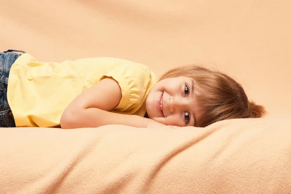 Den leende flickan ligger på en soffa — Stockfoto