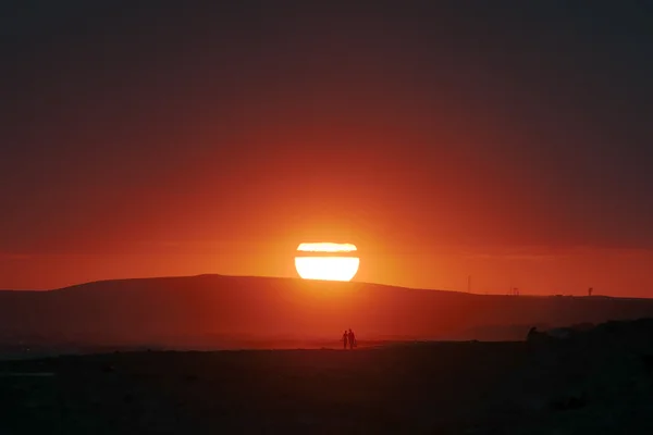 Schöne Landschaft: Mann und Frau am Strand bei Sonnenuntergang lizenzfreie Stockbilder