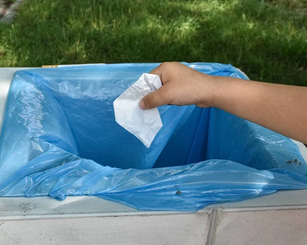 Çocuk özel bir çöp kutusuna bir parça kağıt atıyor.