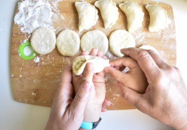 Bir çocuk, bir yetişkinle köfte heykeli yapıyor.