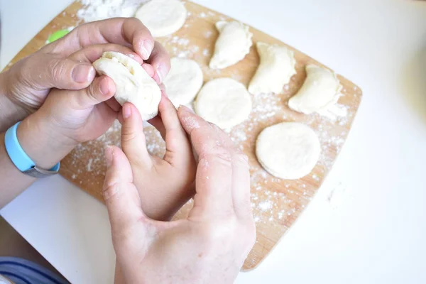 Çocuk ve yetişkin elleri köfte yontuyor.