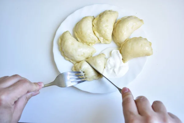 Bir insan ekşi kremayla Vareniki yer.