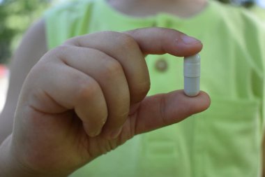 fingers hold a pill