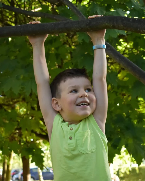 Çocuk bir ağaç dalına asılı.