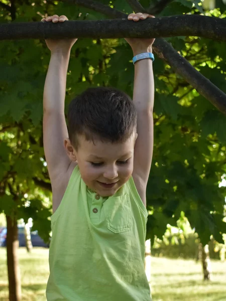 Çocuk bir ağaç dalına asılı.