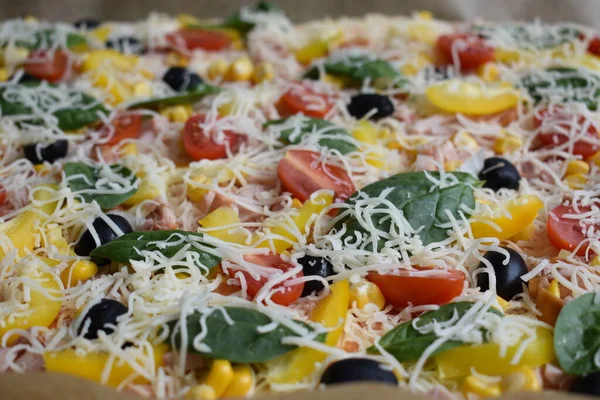 Pişirmeden önce rendelenmiş peynirli pizza