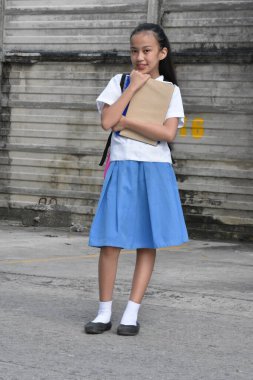 Okul üniforması giymiş okul kitaplarıyla ayakta duran bir kızın portresi.