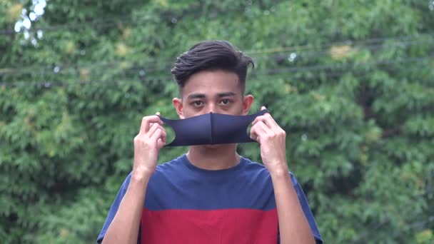 Ein männlicher asiatischer Junge entfernt Gesichtsmaske — Stockvideo