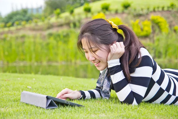 Молода жінка використовує планшет на траві — стокове фото