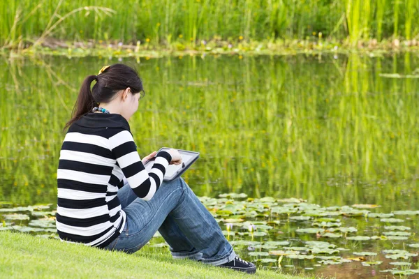 Młoda kobieta za pomocą tabletu nad jeziorem — Zdjęcie stockowe