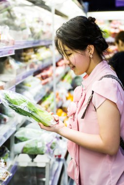 Woman choosing chinese cabbage at supermarket clipart