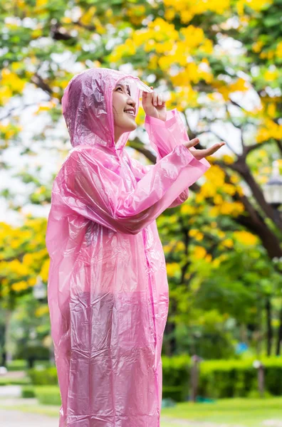 Asiatin in rosa Regenmantel checkt Regen im Garten — Stockfoto