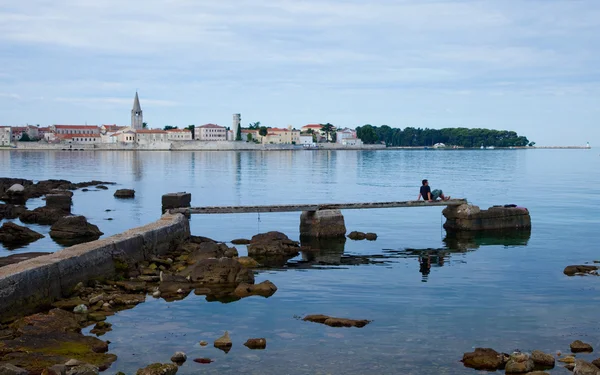 The young man looks at the morning city of Porech, Croatia — Stock Photo, Image