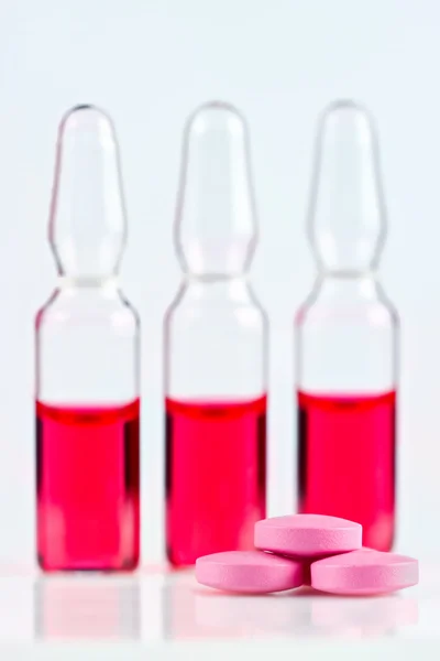Comprimido rosa com ampolas vermelhas — Fotografia de Stock