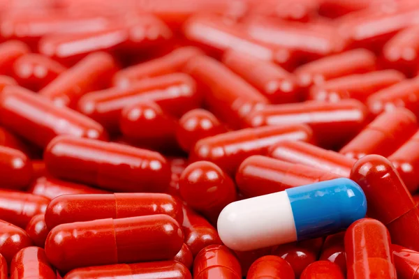 Pílulas azuis e brancas no fundo de pílulas vermelhas — Fotografia de Stock