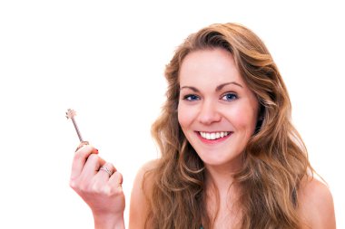 Happy young woman smiling holding a door key clipart