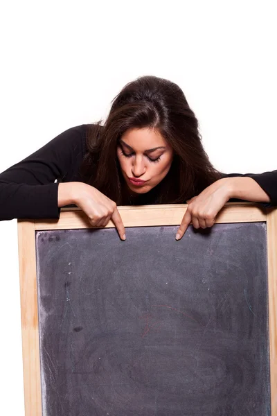 Attractive young woman pointing at a blank blackboard. — Stock Photo, Image