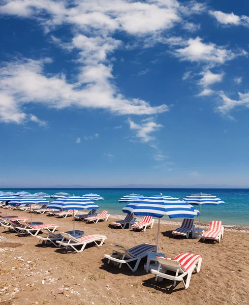 Plage avec parasols et chaises longues sous le soleil et le ciel bleu — Photo