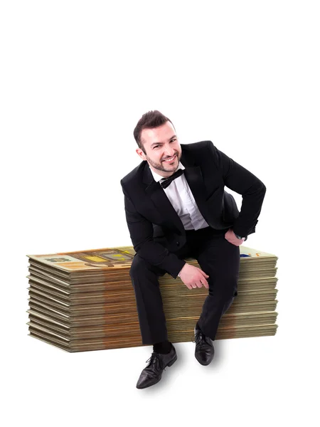 巨大なスタックお金に笑みを浮かべて座っている男します。 — ストック写真