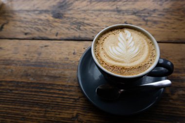 Cappucinno kafeteryadaki ahşap bir masada servis edilir, metin için yer vardır. 