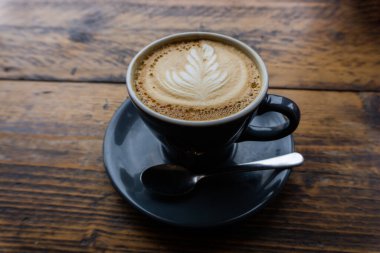 Cappucinno, kafeteryadaki ahşap bir masada servis edilir.