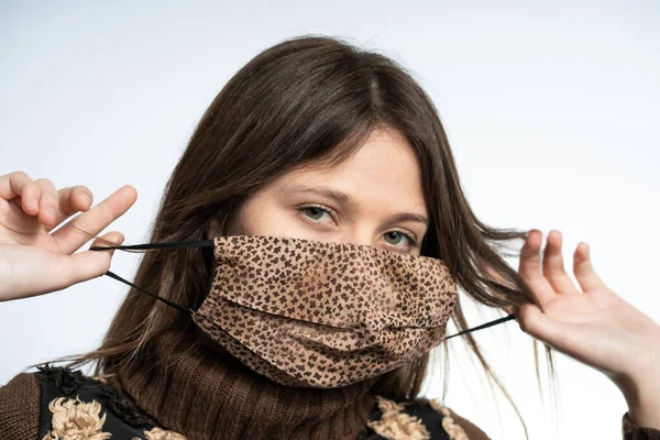 Woman having fun with a mask wearing brown mask, protecting herself from covid